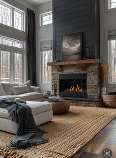 a living room filled with furniture and a fire place in front of two windows on either side of the fireplace