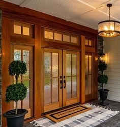 a front door with two potted plants on the side and an entry mat in front