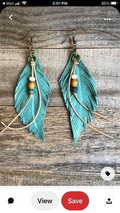 a pair of earrings with wooden beads and feathers on the ear wires, sitting on a wooden table