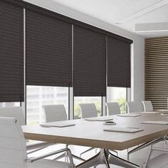 a conference room with white chairs and a large wooden table in front of two windows that have roman shades on them