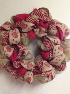 a red and tan wreath with hearts on it hanging on a wall next to a white wall