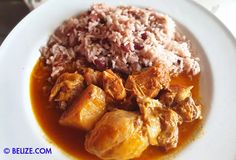 a white plate topped with rice and meat covered in gravy on top of a table