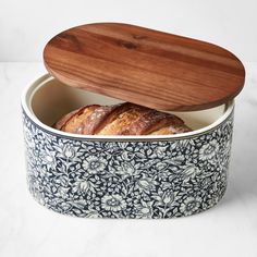 two croissants in a blue and white patterned container with a wooden lid