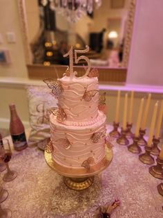 a pink cake sitting on top of a table next to wine glasses and candles in front of a chandelier