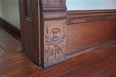 the corner of a wood paneled window with carved designs on it's sides