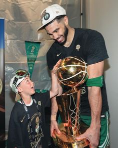 a man and boy holding up a basketball trophy