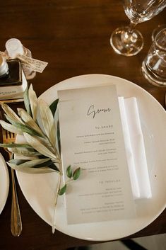 a place setting with menus and wine glasses on the table, along with silverware