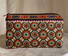 "Small Silk Petit Point Clutch, Handbag Organizer, Make Up Organizer created and handmade in Uzbekistan. Lined with silk and cotton fabric, zipper top.  Each clutch is hand drawn on to cotton canvas, inspired by original designs from Uzbekistan history.  Measures 5.5\"  high x 9\" width, 8\" opening  Embroidery the same on the front and the back of the clutch Can fit largest sizes of iPhone and Android. 100% silk petit point with handwoven silk and cotton lining. Your purchase preserves and enco Traditional Handmade Brown Pouch, Traditional Clutch Coin Purse, Traditional Brown Rectangular Pouch, Artisan Multicolor Clutch As A Gift, Traditional Handmade Pouch With Multicolor Embroidery, Artisan Multicolor Rectangular Clutch, Traditional Handmade Multicolor Embroidered Pouch, Handmade Artisan Rectangular Clutch, Traditional Handmade Clutch Pouch