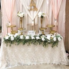 a table topped with white flowers and gold candelabra covered in pink drapes