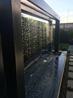 a water fountain in the middle of a garden with rocks and grass on either side