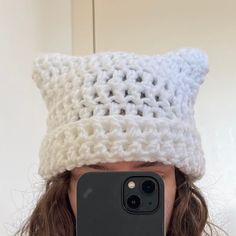 a woman taking a selfie in front of her phone wearing a crocheted hat