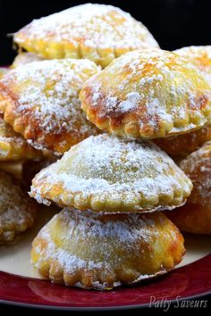 several pastries are piled on top of each other in a plate with powdered sugar