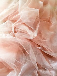 an abstract photo of pink and white tulle on a bed sheet with soft light coming from the top