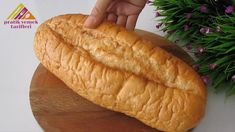 a loaf of bread sitting on top of a wooden cutting board next to purple flowers