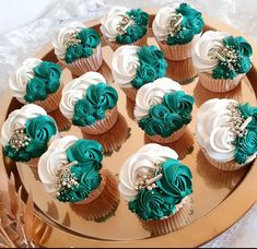 there are many cupcakes with green and white frosting on the cake plate