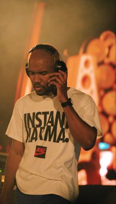 a man with headphones on talking on a cell phone while standing in front of a stage