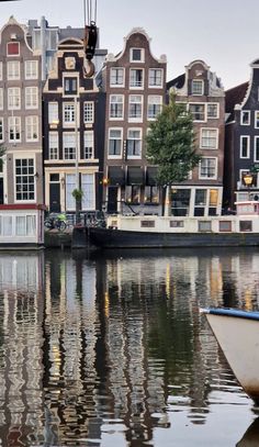 a boat floating on top of a river next to tall buildings