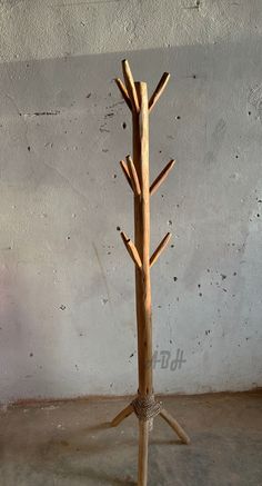 a tree made out of wood sticks is shown in front of a white wall and concrete floor