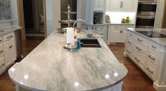 a large kitchen with white cabinets and marble counter tops