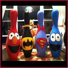 four bowling pins with cartoon characters painted on them sitting on a table in front of a window