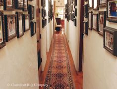 a hallway with pictures on the wall and a rug