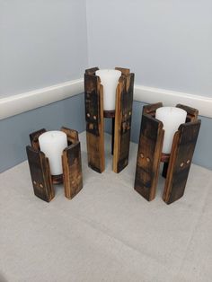 four wooden candle holders sitting on top of a white floor next to a gray wall