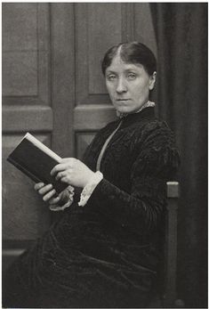 an old black and white photo of a woman holding a book