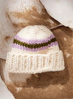 a white knitted hat laying on top of sand