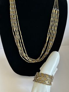 "Chico's Gold Tone and Iridescent Beaded Necklace & Bracelet Set. Gorgeous together or worn separately this set will add style to any outfit.  Alternating metal oblong beads with iridescent gray beads.  Bracelet is the same and adjustable with its spring wrap form.  Pre-owned, in great condition. Necklace is 16\" length with. 4\" extender Bracelet has a 2.5\" opening." Adjustable Gold Beads For Costume Jewelry, Gold Multi-strand Beaded Necklace With Silver Beads, Gold Metal Beads Bracelet, Gold Beaded Metal Jewelry, Gold Jewelry With Polished Metal Beads, Gold Multi-strand Large Beaded Jewelry, Gold Multi-strand Jewelry With Large Beads, Gold Beaded Necklace With Silver Beads, Gold And Silver Beaded Costume Jewelry Necklace