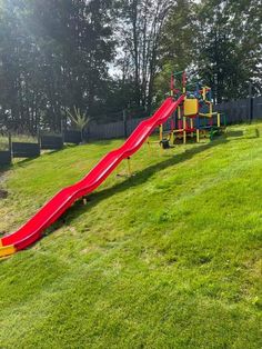 a red slide in the middle of a grassy field