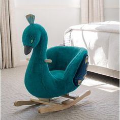 a blue rocking duck toy sitting on top of a floor next to a white bed