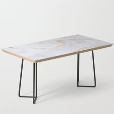 a white table with black metal legs and a pattern on the top, against a white background