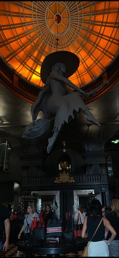 people are walking around in the lobby of a building with a ceiling light above it