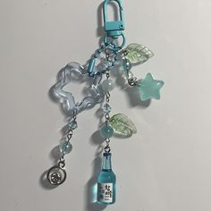 a blue bottle with charms hanging from it's side on a white table top