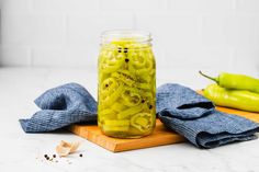 a jar filled with pasta sitting on top of a wooden cutting board next to peppers