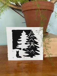 a black and white card sitting on top of a wooden table next to a potted plant