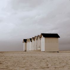 a row of beach huts sitting on top of a sandy beach