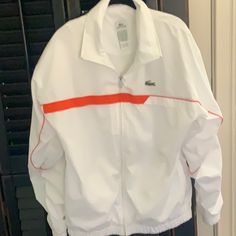 Chanel The 90’s In This Brand New Lacoste Sports Tennis Jacket Arm Pit To Arm Pit Is 23” Top Of Shoulder To Hem Is 29” Elastic On Bottom And Cuffs 100% Polyester Lining Is Polyester And Cotton Machine Wash Zips Up The Front Size 5 Large Rene Lacoste Designed A Tennis Champion Sporty White Windbreaker For Sports Season, White Sports Windbreaker, White Sporty Track Jacket With Pockets, White Athleisure Track Jacket With Pockets, White Sporty Sport Coat, Sporty White Sport Coat, White Hooded Windbreaker For Sports Season, White Hooded Windbreaker, Casual White Long Sleeve Sport Coat