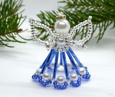 an ornament made out of glass beads and pearls on a white background with pine branches