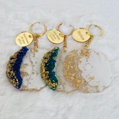 four different colored marble key chains on a white furnishing with gold disc charms