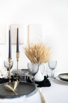 the table is set with silver dishes and black candlesticks, pamodia