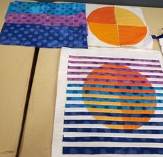 three pieces of art made with different colors and patterns on a table top next to a pair of scissors