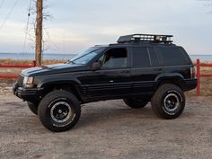 a black suv parked on top of a dirt field