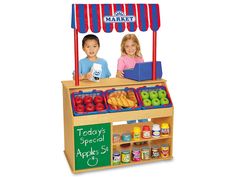 two children are standing behind a food stand