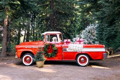 an old red truck with a christmas tree in the bed and presents on the back