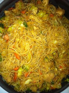 a pan filled with noodles and veggies on top of a stove burner