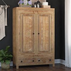 a wooden cabinet sitting on top of a hard wood floor next to a potted plant