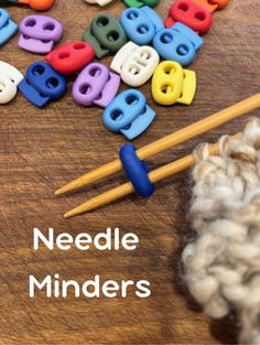 the needles are next to some yarn and knitting needles on a wooden surface with letters that spell needle minds