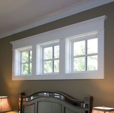 a bedroom with two lamps on either side of the headboard and windows above it