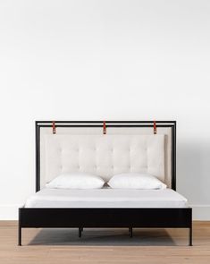 a bed with two pillows on top of it and an iron frame in the middle